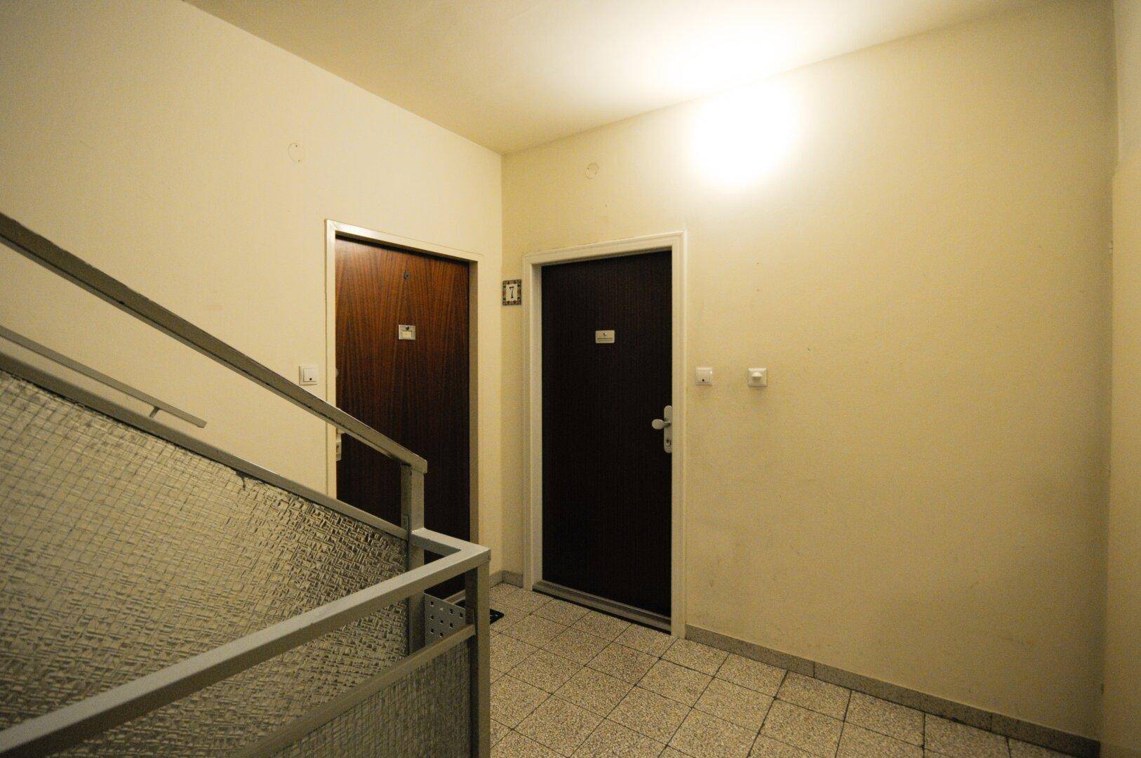 Eingangsbereich im Mehrfamilienhaus mit Treppenhaus und Zugang zu den einzelnen Wohneinheiten.