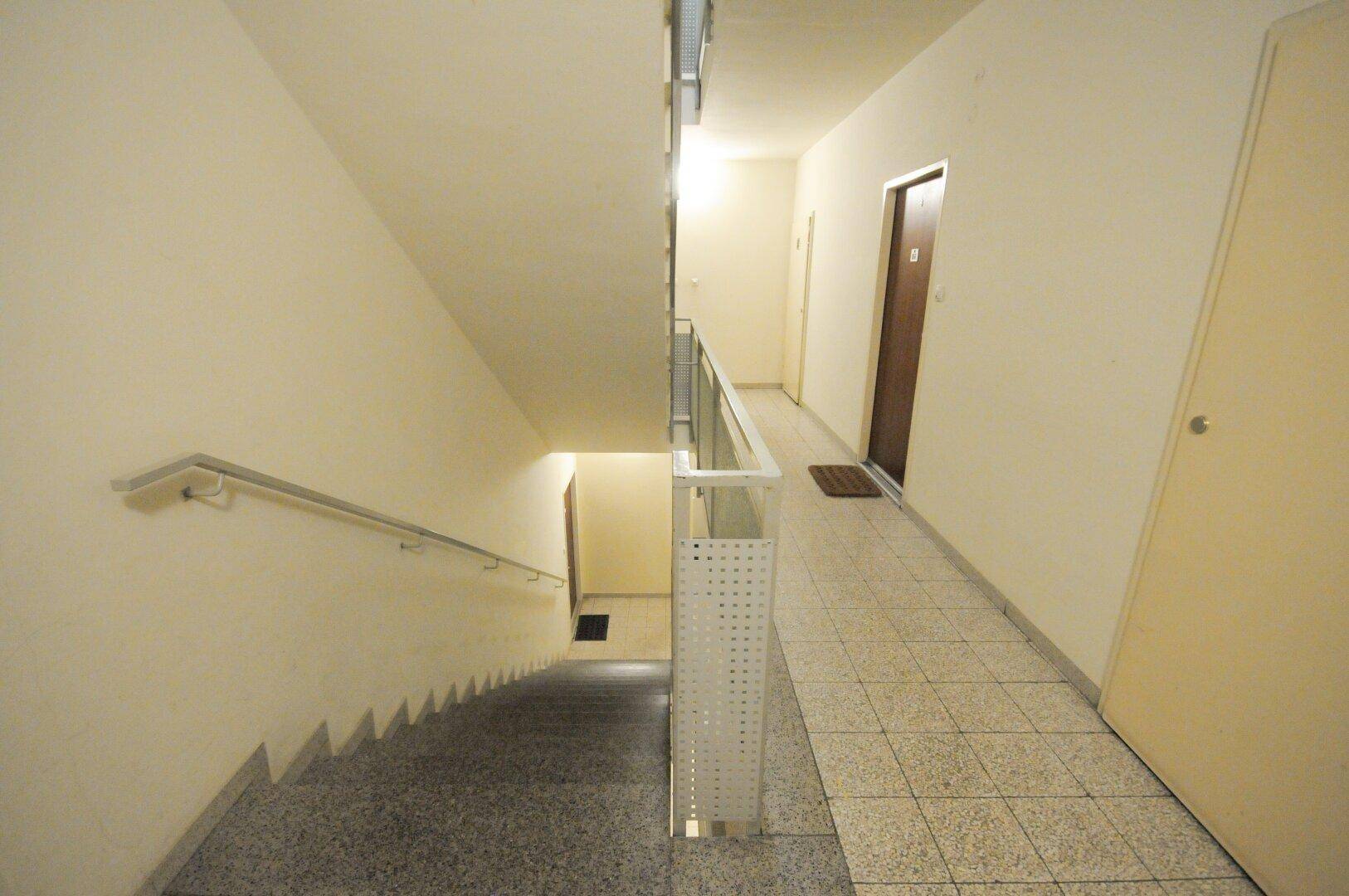 Treppenhaus im Mehrfamilienhaus mit Geländer und Zugang zu den verschiedenen Etagen.