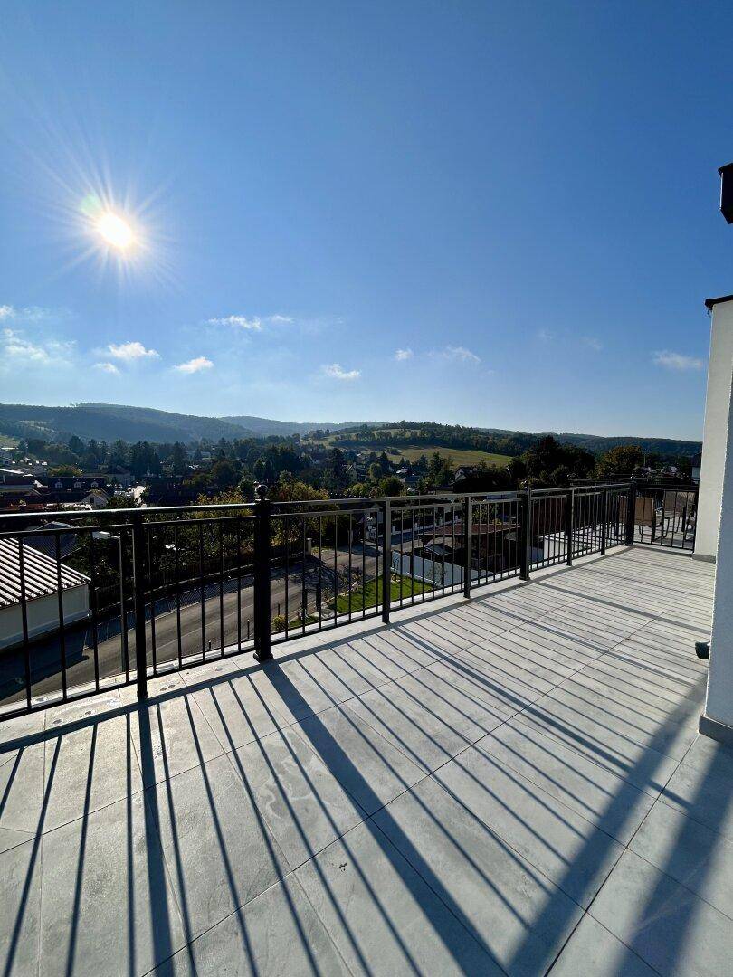 Sonniger Tag auf der Dachterrasse mit weitem Blick über die hügelige Landschaft.