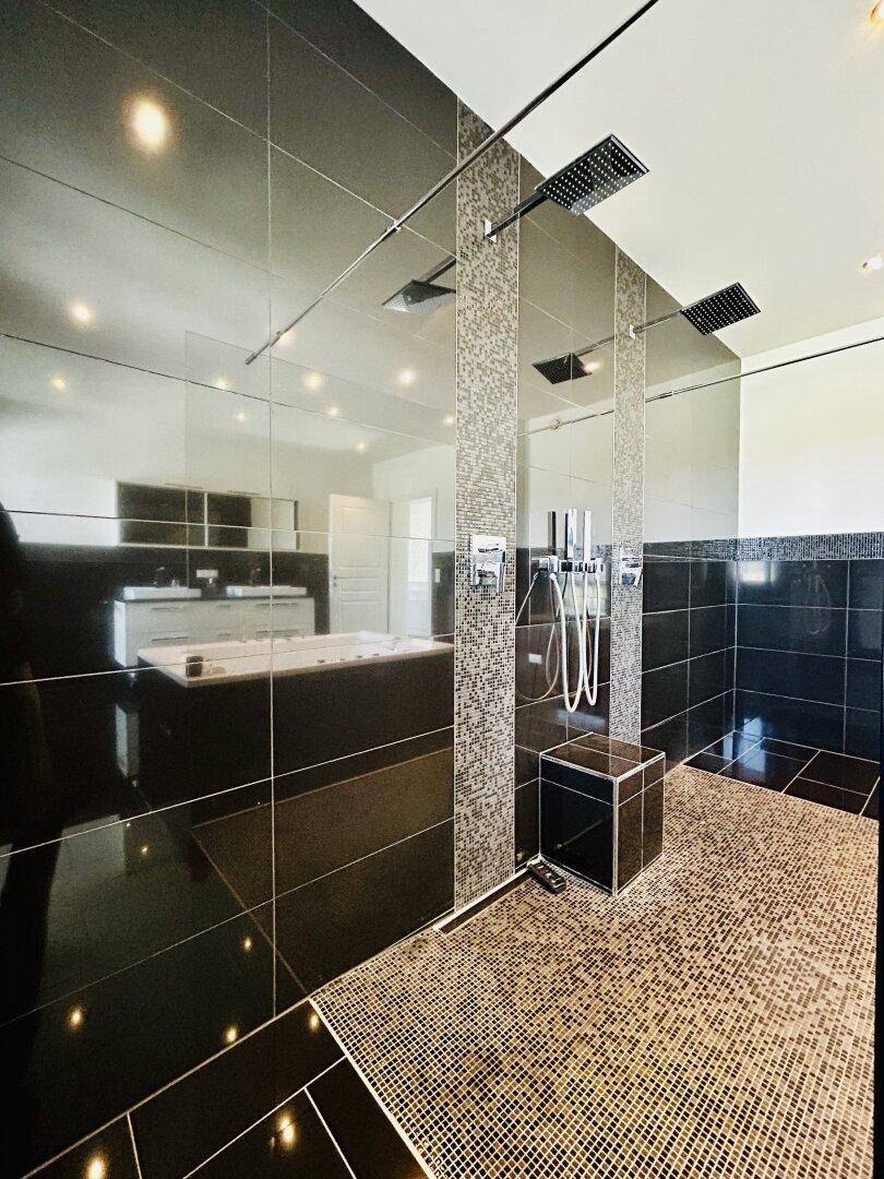 Geräumige begehbare Dusche mit Regenduschköpfen und stilvollen Mosaikfliesen.