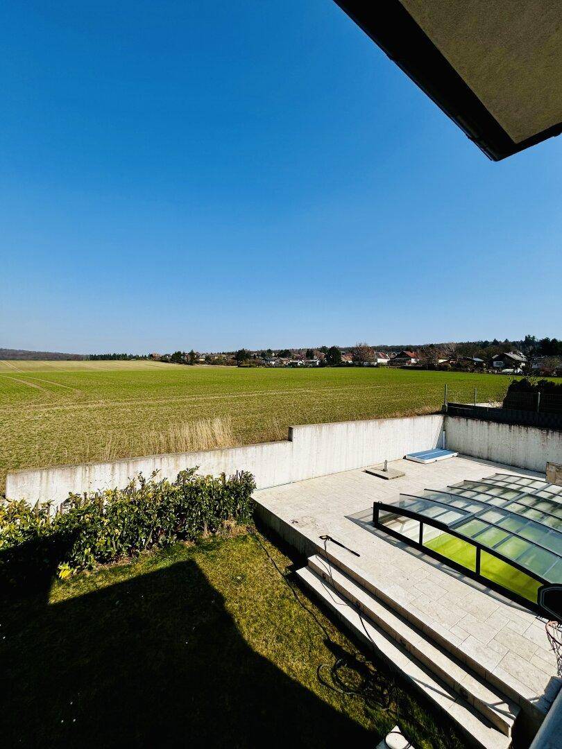 Weitläufiger Garten mit Poolbereich und freiem Blick auf die umliegende Natur.