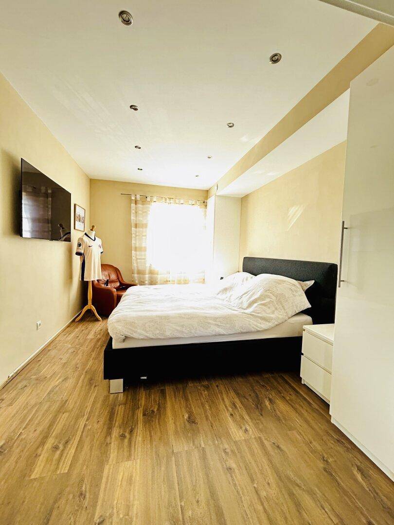 Gemütliches Schlafzimmer mit Doppelbett, Holzboden und viel Tageslicht.