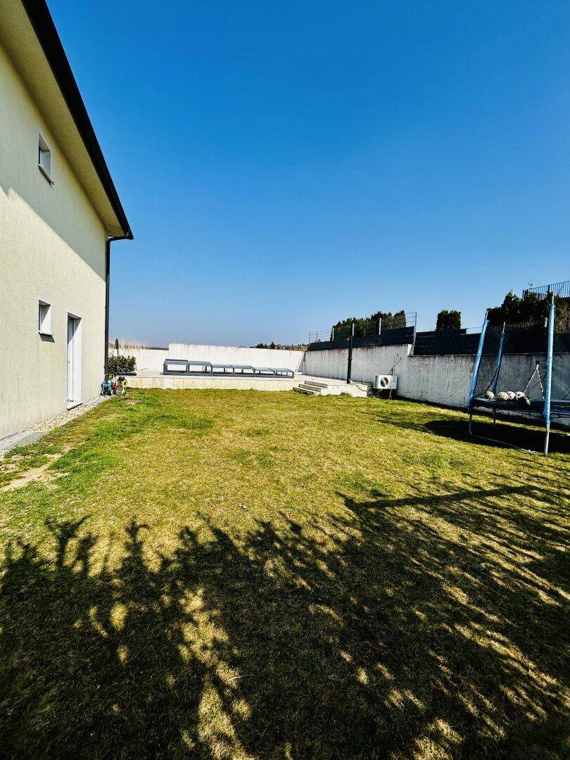 Weitläufiger Gartenbereich mit Rasenfläche, Trampolin und viel Platz im Freien.