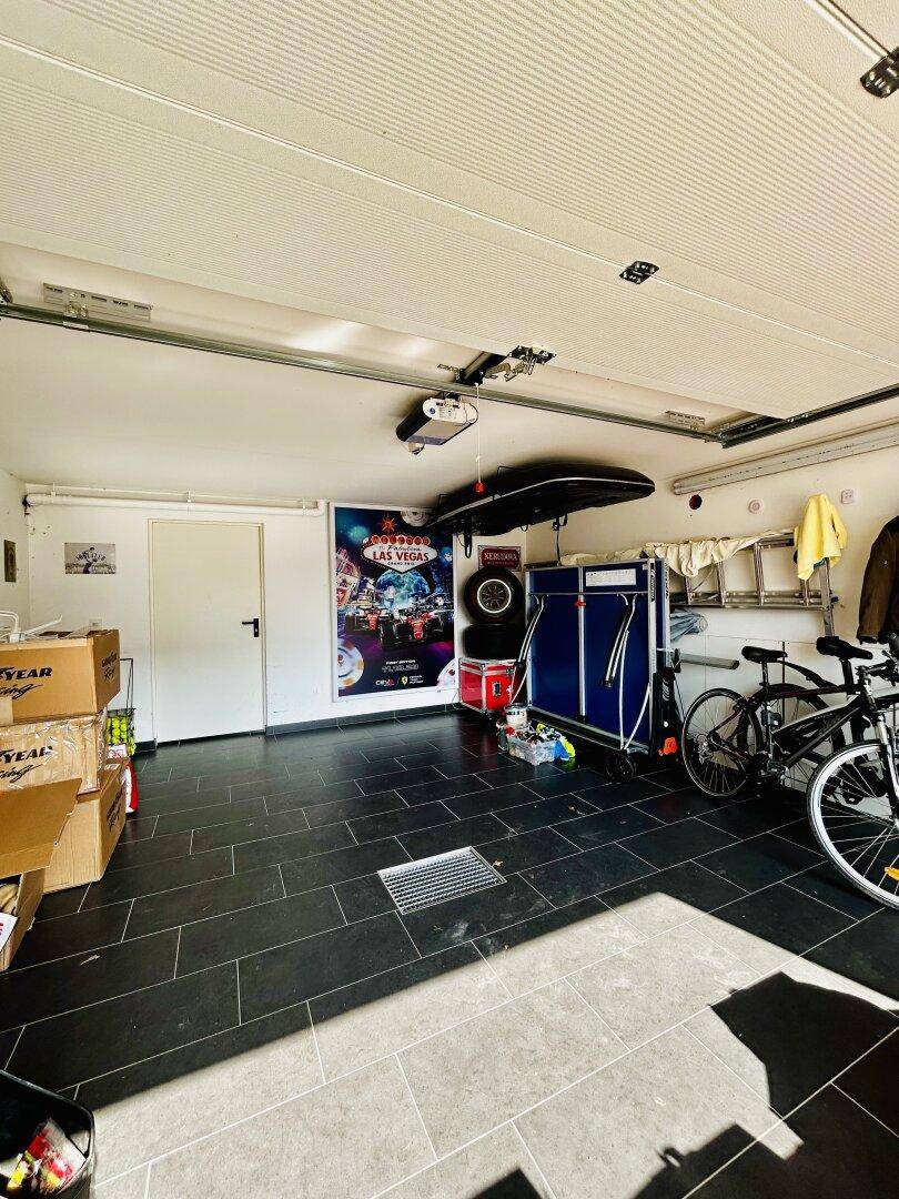 Geräumige Garage mit Fliesenboden, Stauraum und Platz für Fahrräder und Sportgeräte.