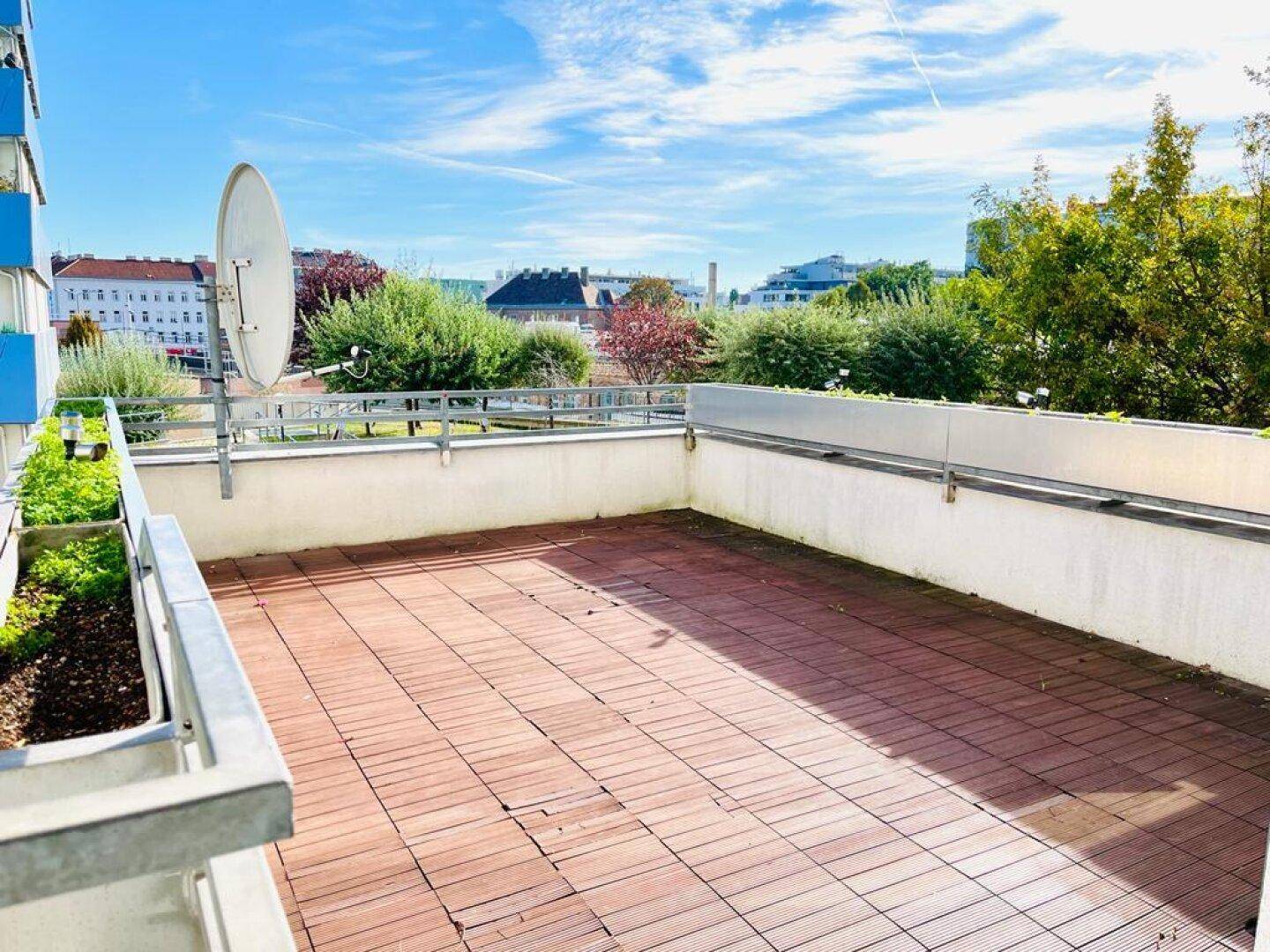 Geräumige Dachterrasse mit Holzdielenboden und weitem Blick über die Stadt und ins Grüne.