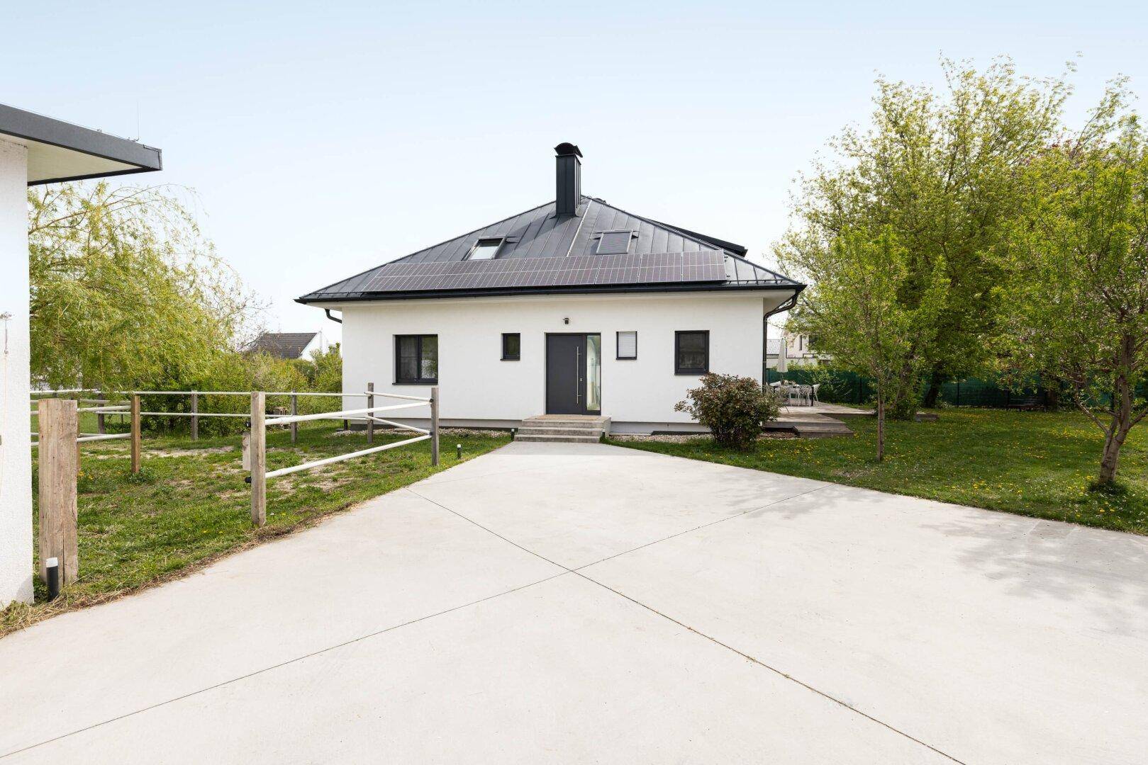 Vorderansicht des modernen Einfamilienhauses mit Zufahrt und separatem Nebengebäude.