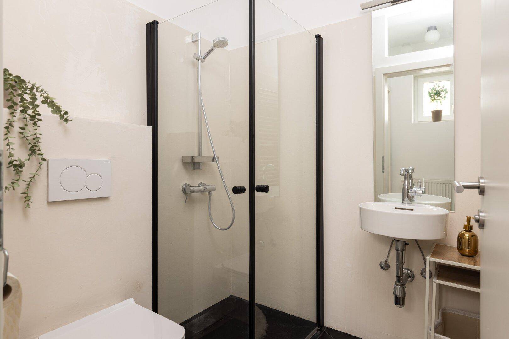 Kompaktes Badezimmer mit Dusche, wandhängendem WC und modernem Waschbecken.
