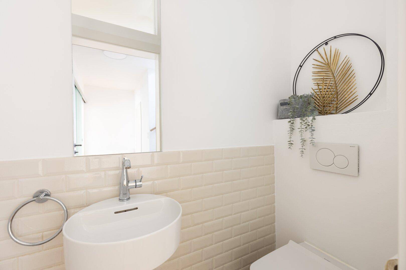 Modernes Gäste-WC mit kleinem Waschbecken und wandhängender Toilette.