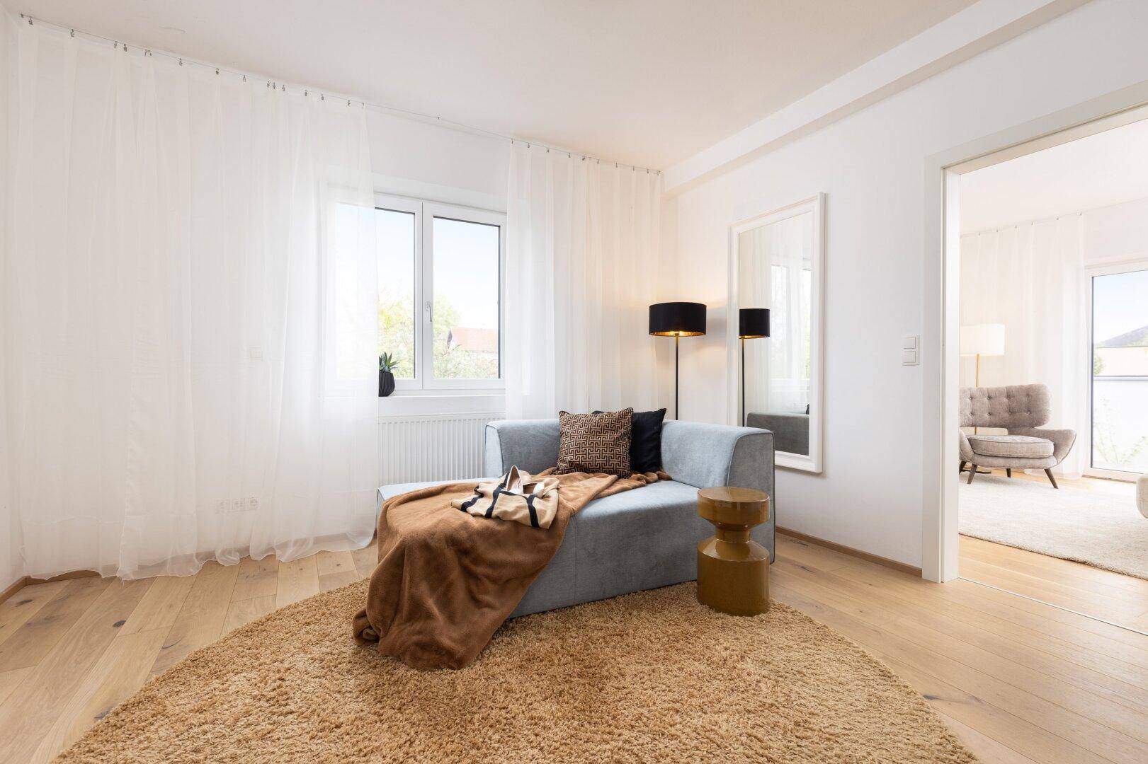 Gemütlicher Lounge-Bereich mit Chaiselongue, Stehlampe und großem Spiegel.