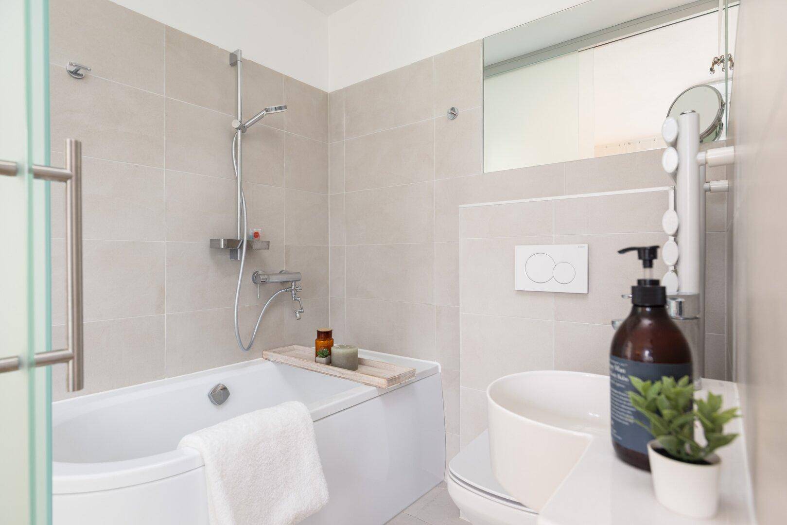 Helles Badezimmer mit Badewanne, WC und modernem Waschbecken.