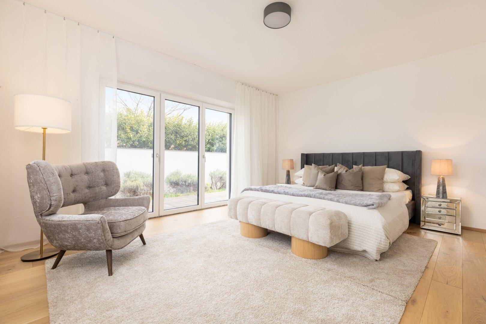 Geräumiges Schlafzimmer mit großem Bett, Teppichboden und Zugang zu einer Außenterrasse.