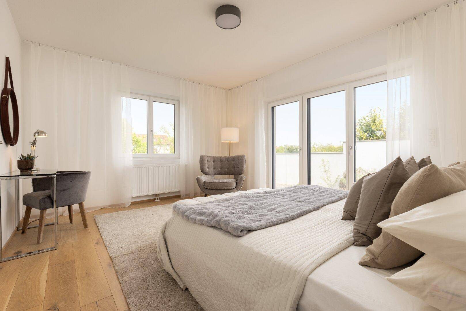 Geräumiges Schlafzimmer mit großem Bett, Teppichboden und Zugang zu einer Außenterrasse.