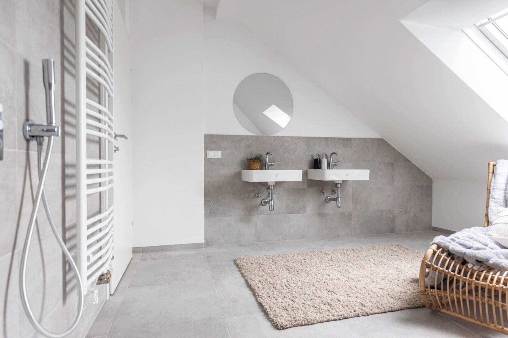 Modernes Badezimmer im Dachgeschoss mit Dusche, Doppelwaschbecken und Handtuchheizkörper.