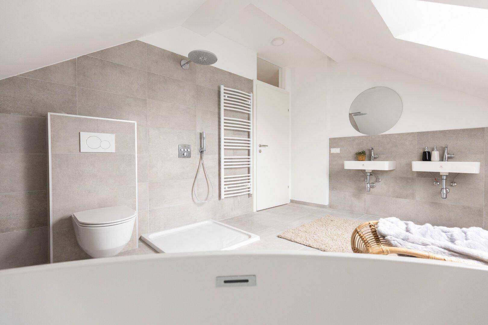 Modernes Badezimmer im Dachgeschoss mit Dusche, Doppelwaschbecken und Badewanne.