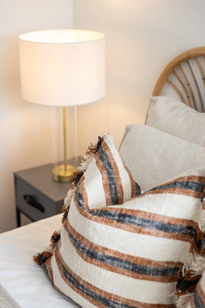 Detailansicht von Kissen auf dem Bett mit Nachttisch und Lampe.