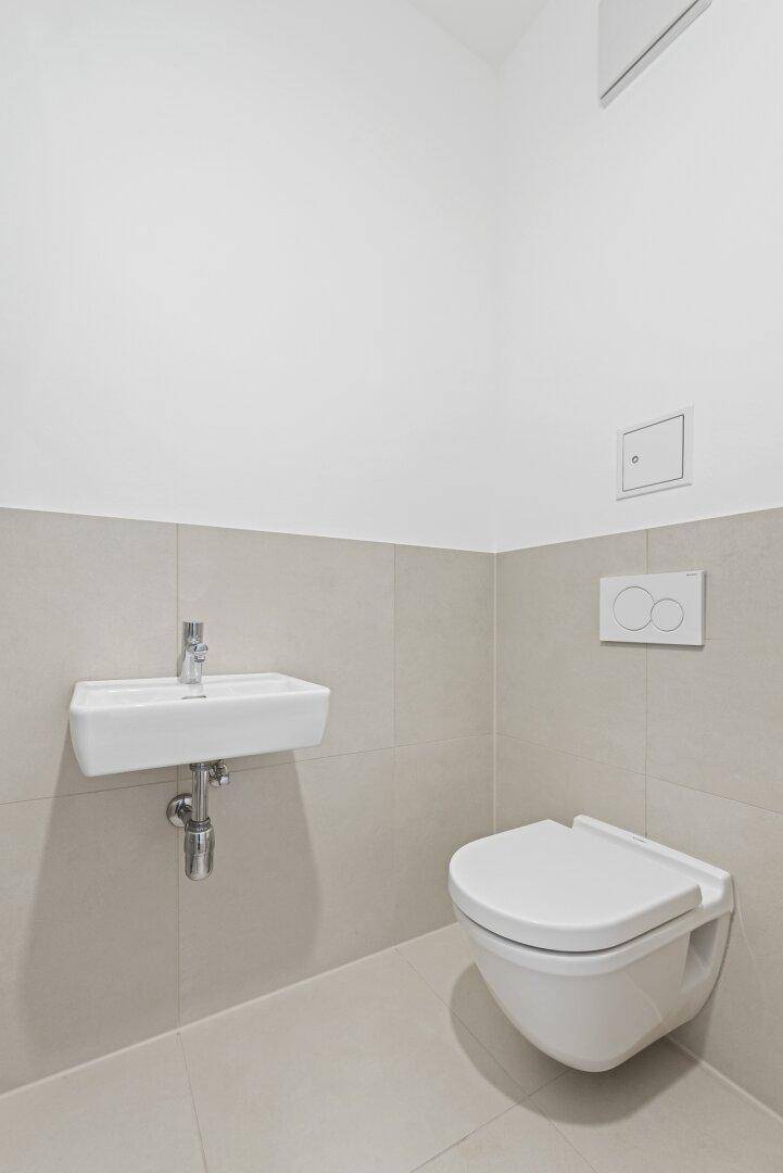 Modernes Gäste-WC mit wandhängender Toilette und kleinem Waschbecken.