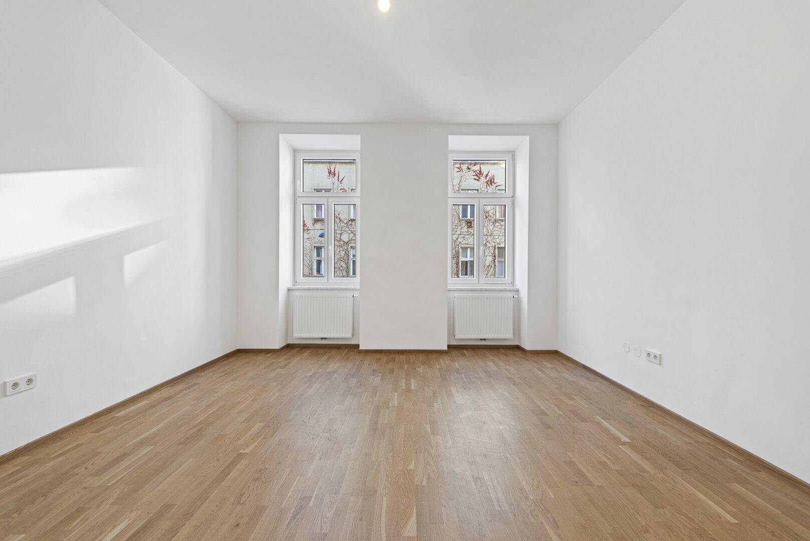 Geräumiges, helles Zimmer mit Parkettboden und zwei großen Fenstern zur Straße.
