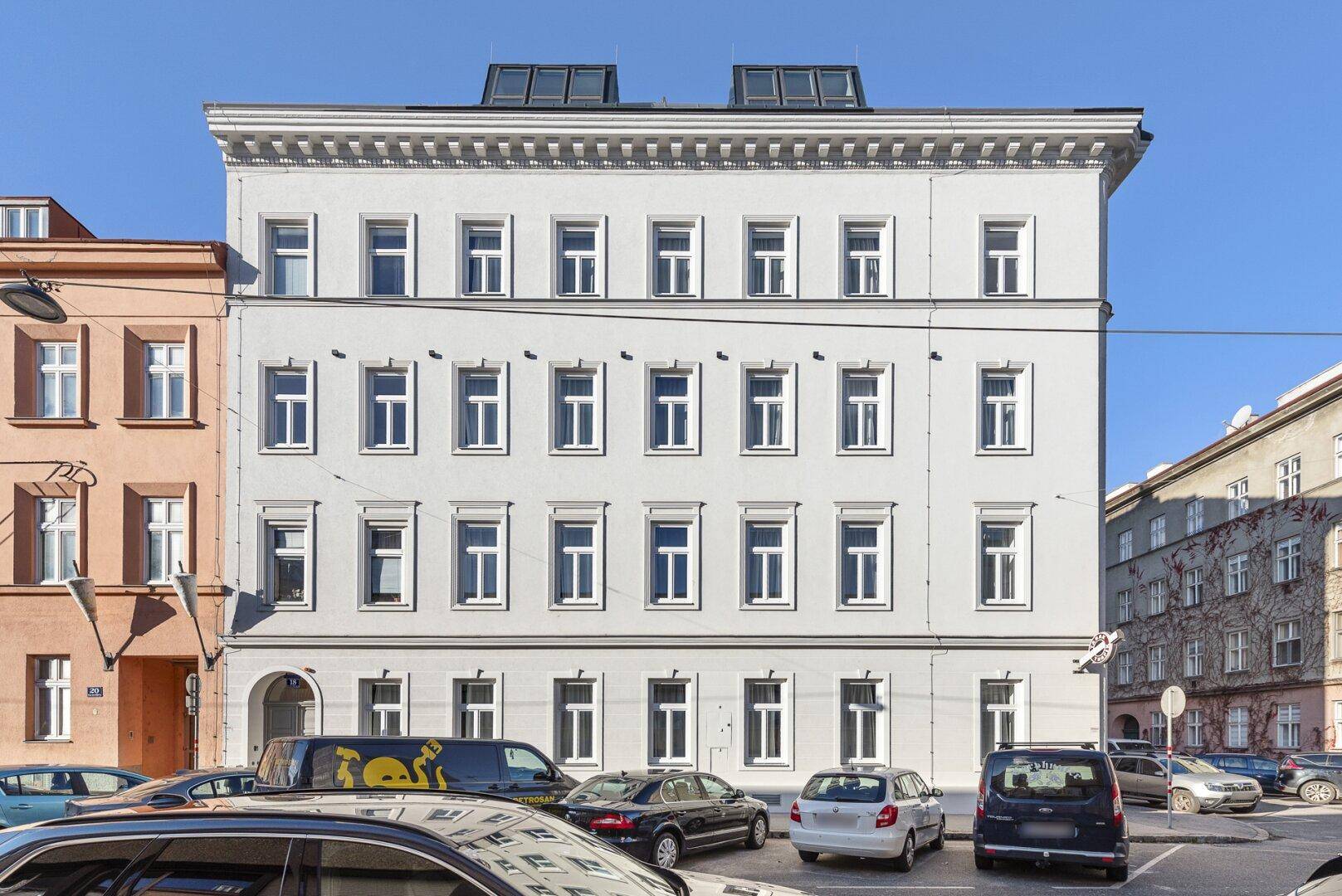 Historisches Gebäude mit klassischer Fassade und Dachgauben in städtischer Umgebung.