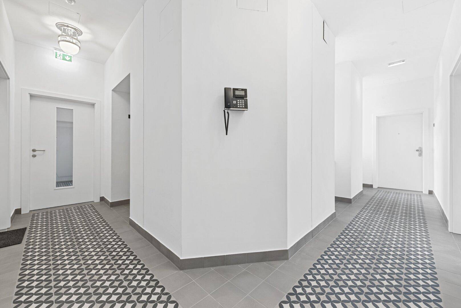 Heller Flur mit modernem Fliesenboden und Gegensprechanlage.