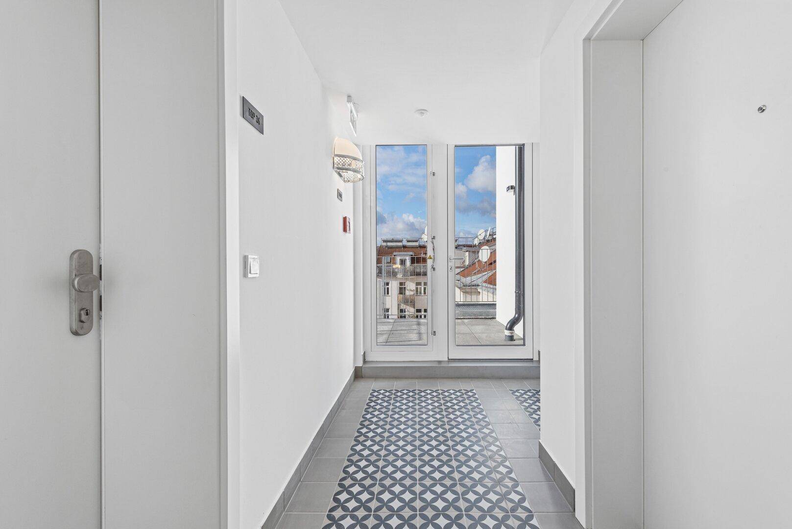 Heller Flur mit Fliesenboden und Zugang zu einem französischen Balkon.
