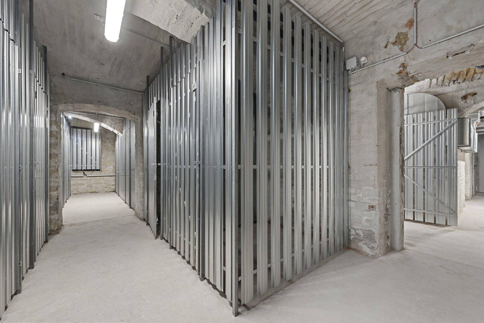 Kellerabteile mit Metallgittern in einem historischen Kellergewölbe.