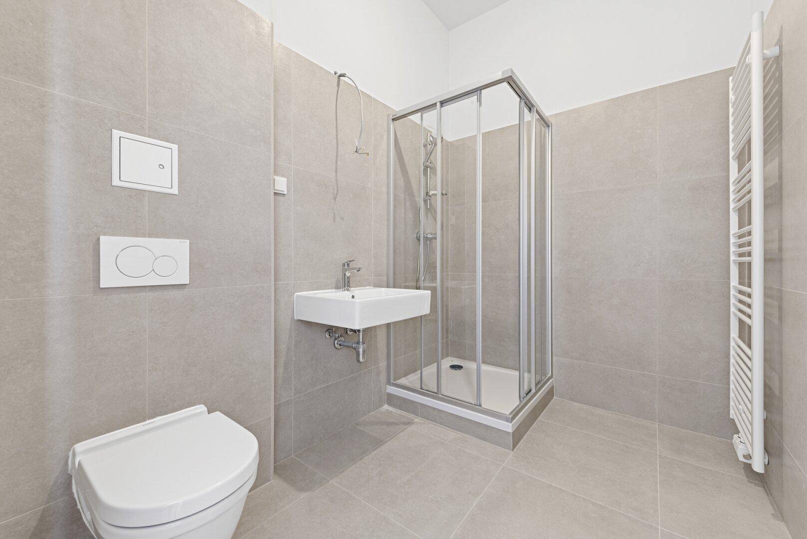 Modernes Badezimmer mit Duschkabine, Waschbecken, Toilette und Handtuchheizkörper.