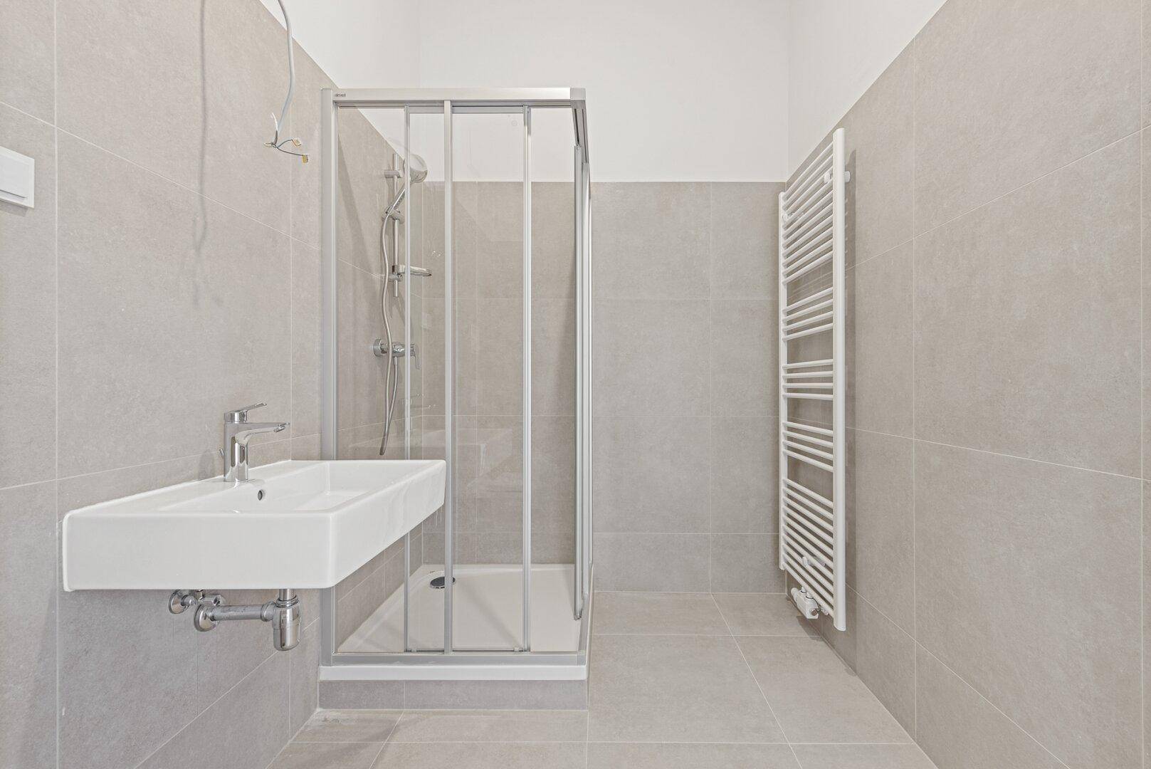 Modernes Badezimmer mit Duschkabine, Waschbecken und Handtuchheizkörper.