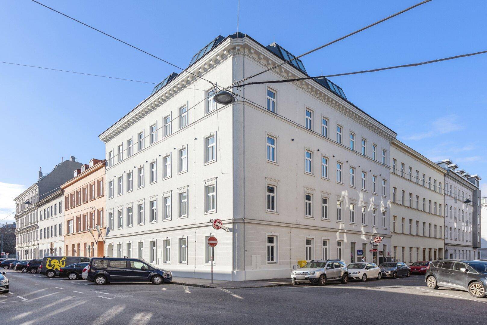 Elegantes Eckgebäude in der Stadt mit klassischer Architektur und vielen Fenstern.