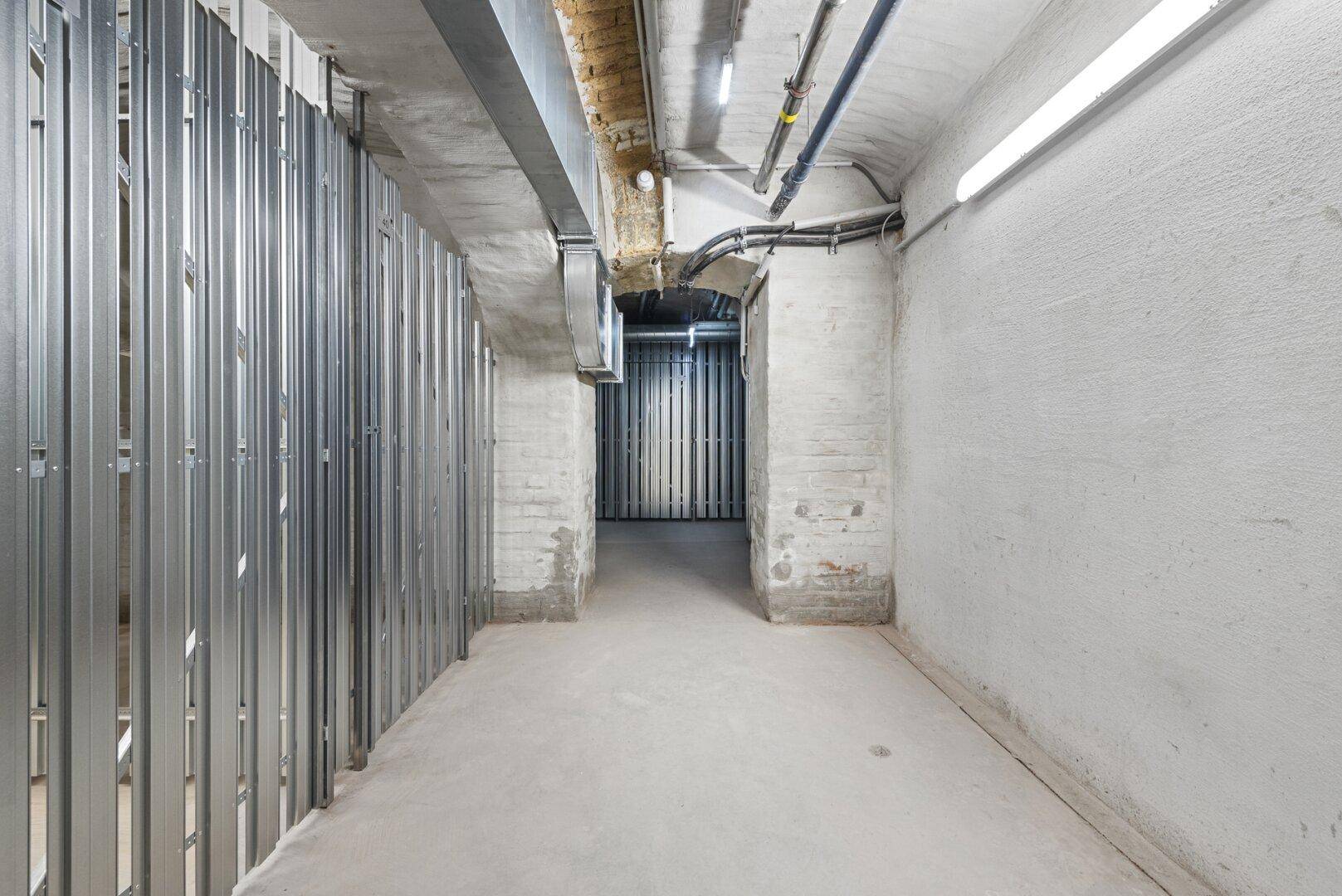 Kellerabteil mit Metallabtrennungen und Betonboden in einem Mehrfamilienhaus, ideal als Stauraum.