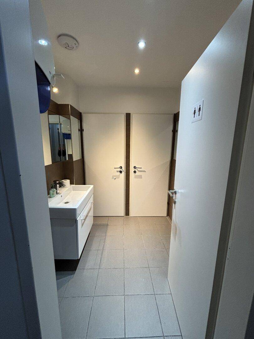 Moderner Sanitärbereich mit Waschbecken und zwei separaten Toilettenkabinen, sauber und funktional.
