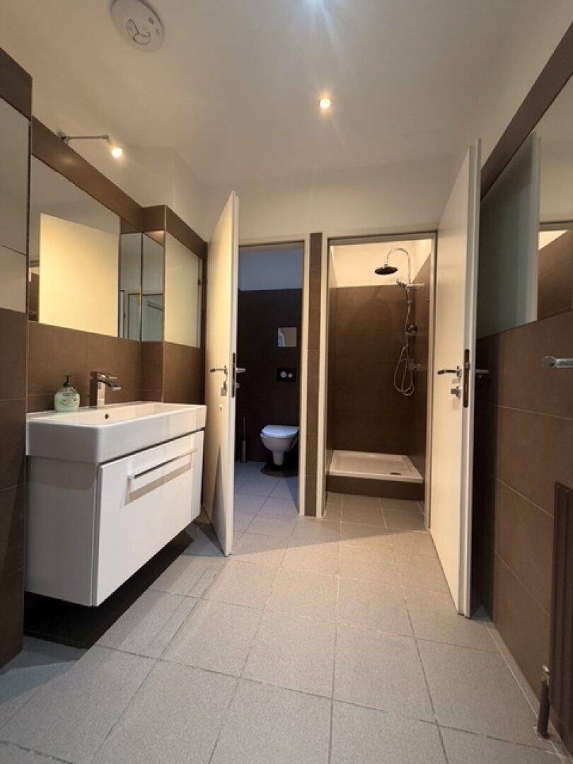 Funktionaler Sanitärbereich mit Waschbecken, separater Toilette und Duschkabine, ideal für den gewerblichen Gebrauch.