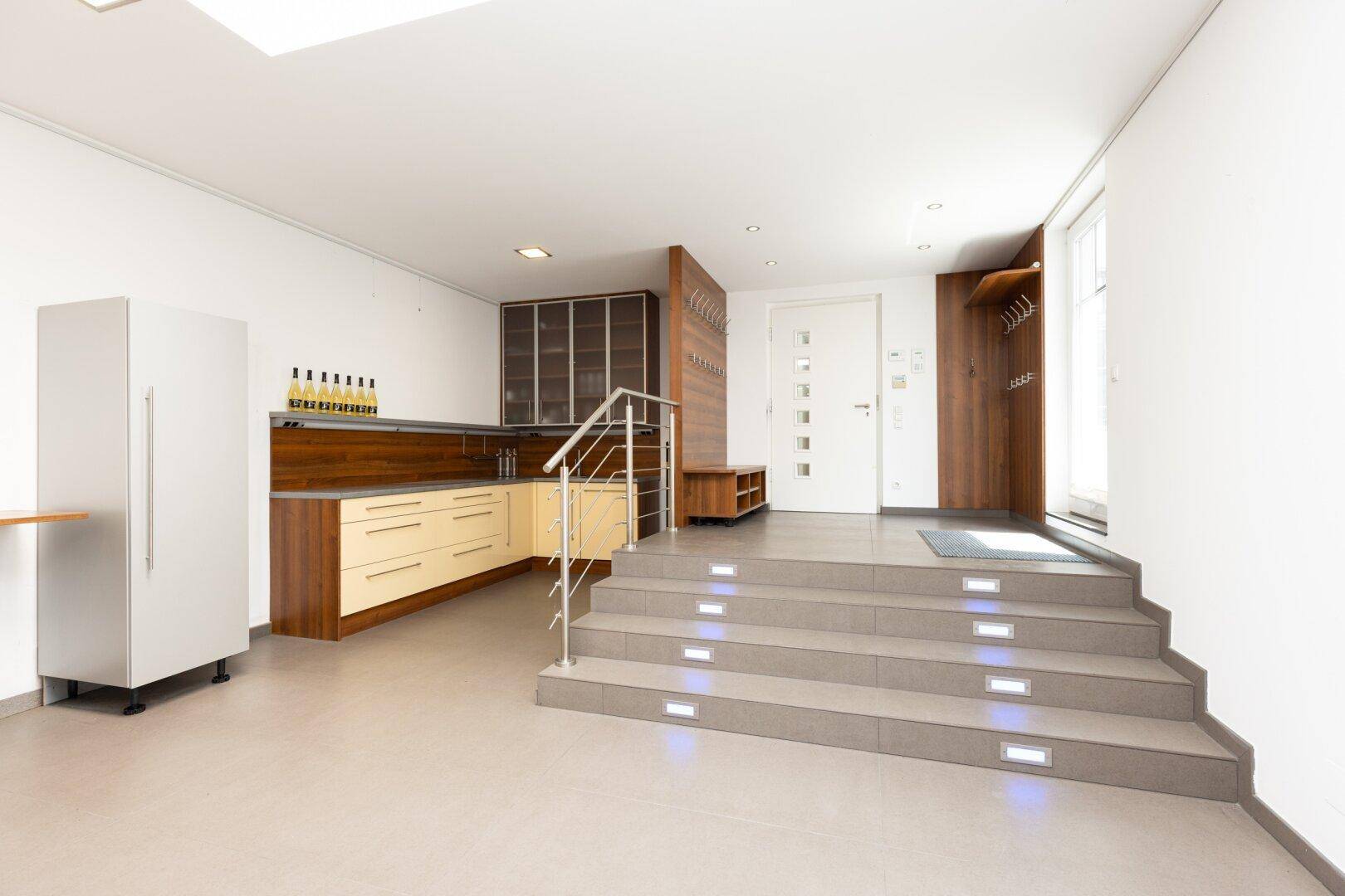 Moderner Eingangsbereich mit integrierter Küchenzeile, Treppe und stilvoller Beleuchtung.