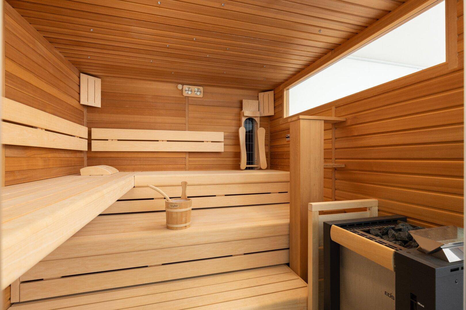 Geräumige Holzsauna mit Bänken und Heizofen, bereit für entspannende Momente.