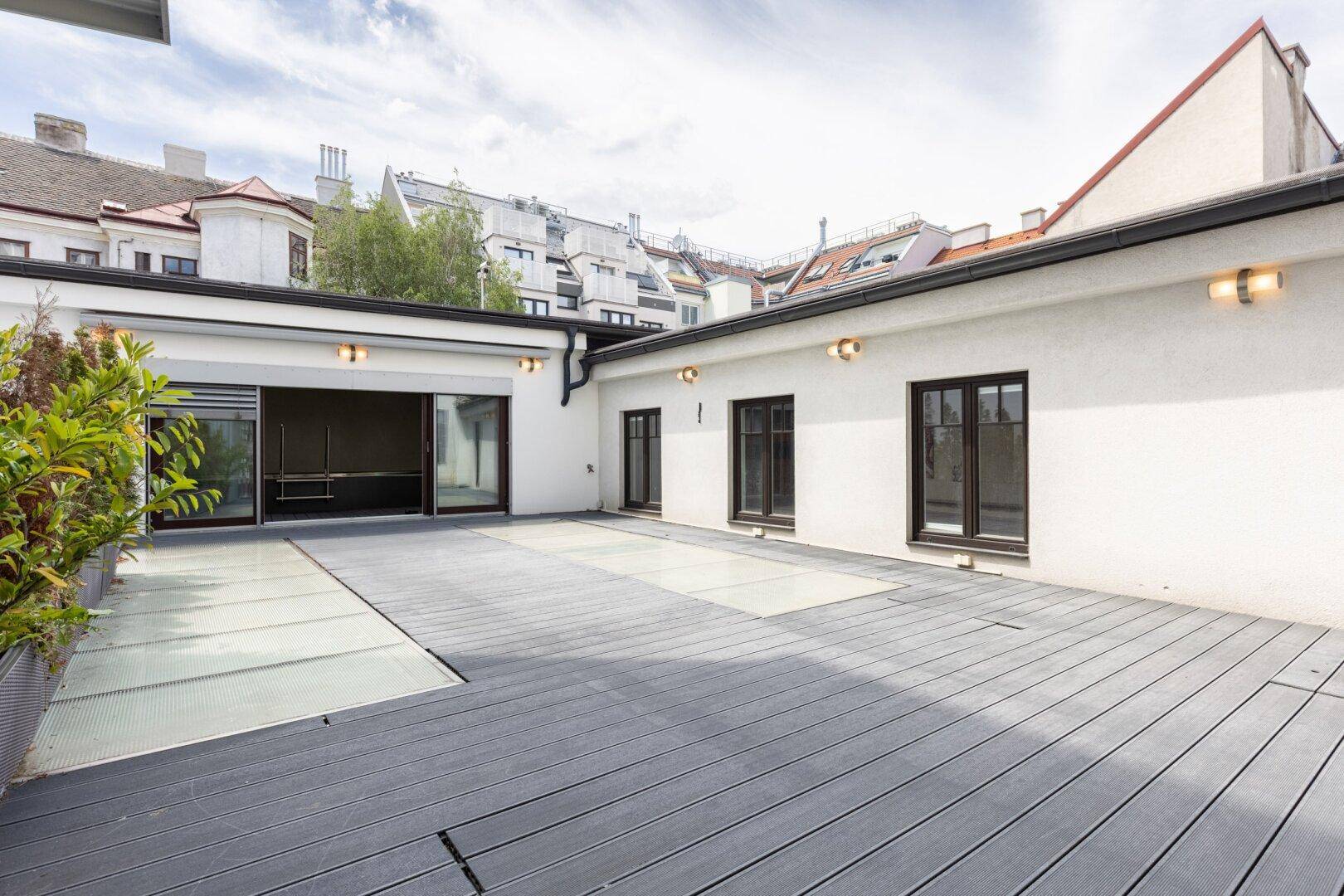 Große Dachterrasse mit Holzdeck und Blick auf die umliegenden Gebäude der Stadt.