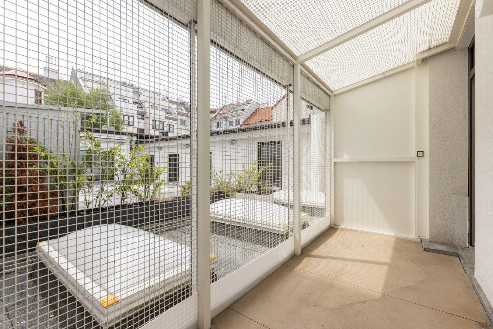 Überdachter Balkon mit Gitterumrandung und Blick auf die umliegenden Dächer der Stadt.