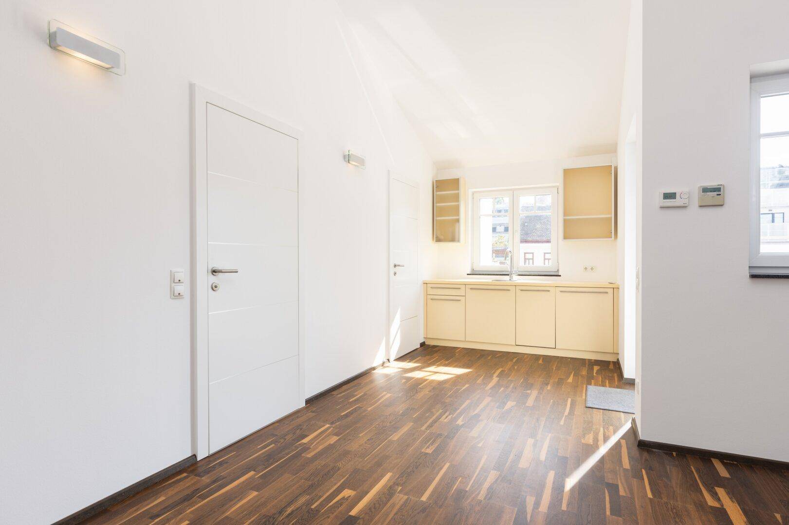 Kleine Küchenzeile im Dachgeschoss mit Holzboden und viel Tageslicht.