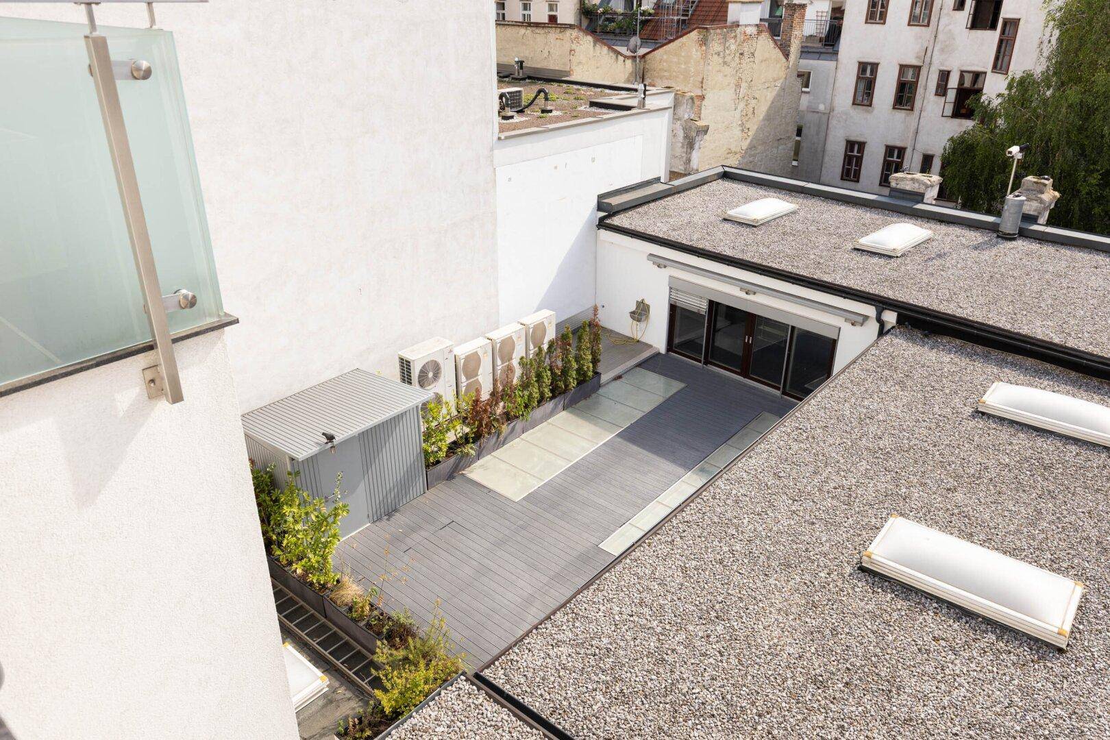 Dachterrasse mit Holzdeck, Grünflächen und Klimaanlagen-Außengeräten.