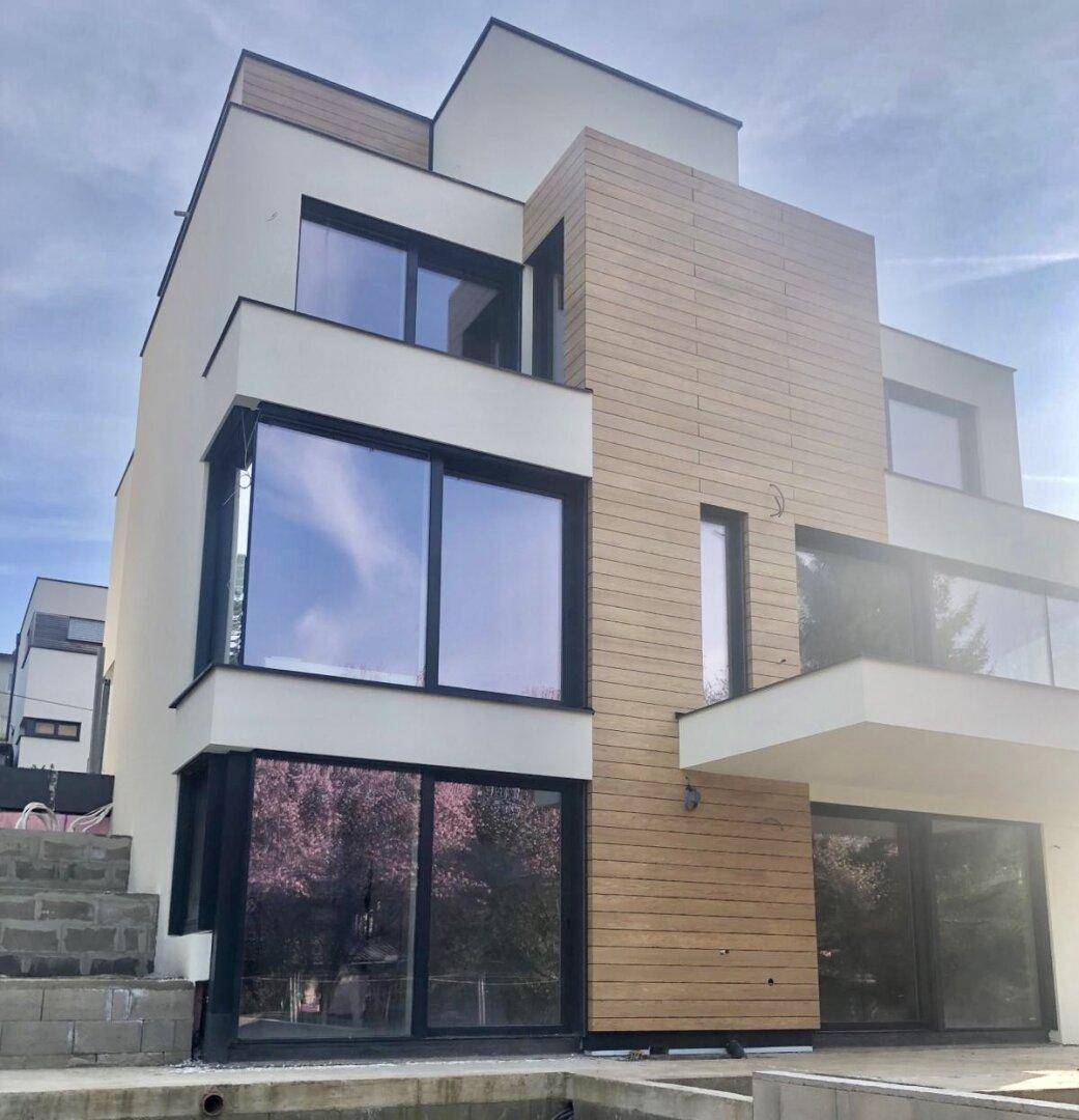 Zeitgenössische Gebäudefassade mit großen Fenstern und stilvoller Holzverkleidung, die moderne Architektur betont.
