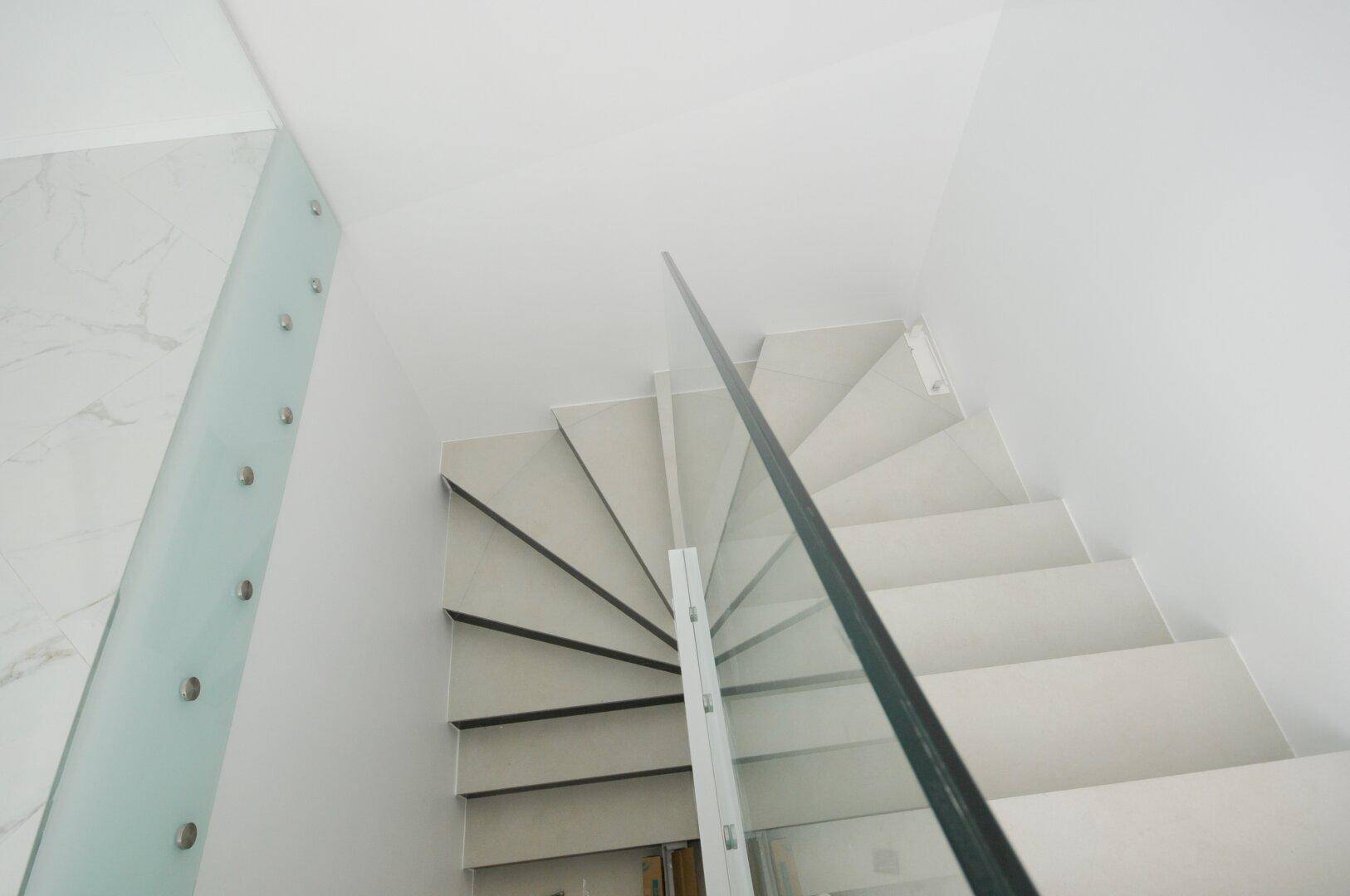 Moderne Treppe mit Glasgeländer und Marmorstufen, die in die obere Etage führt.