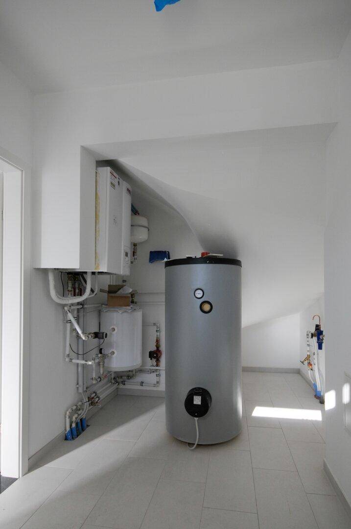 Technikraum mit Warmwasserspeicher und sichtbaren Installationen, funktional und gut organisiert.