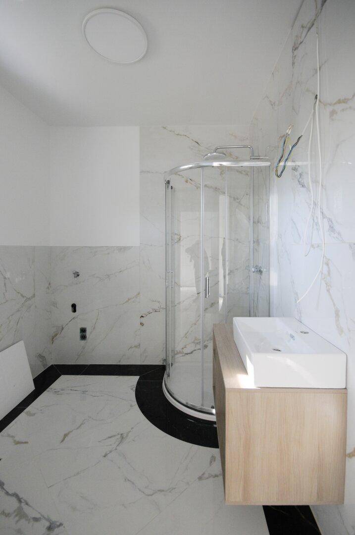 Modernes Badezimmer mit Marmorfliesen, Glasdusche und schwebendem Waschtischunterschrank.