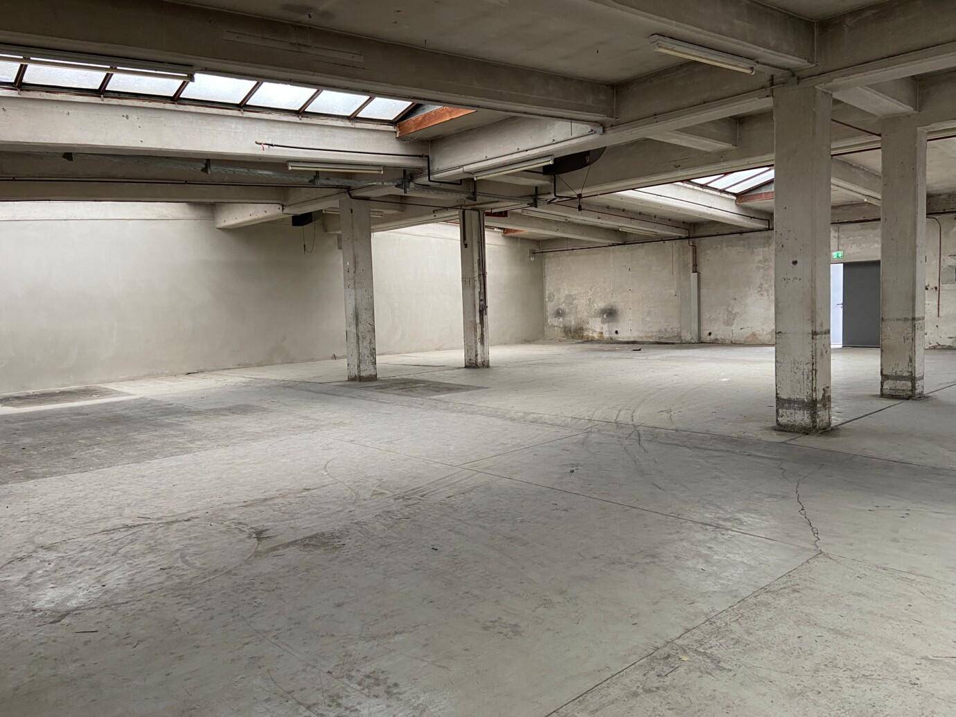 Heller, offener Industrieraum mit vielen Säulen, Betonboden und Oberlichtern für Tageslicht.