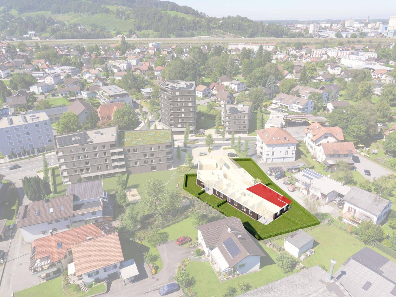 Eine Luftaufnahme, die ein neues Wohngebäude mit rotem Dach hervorhebt, umgeben von Bestandsgebäuden und viel Grünfläche (Rheindorf).