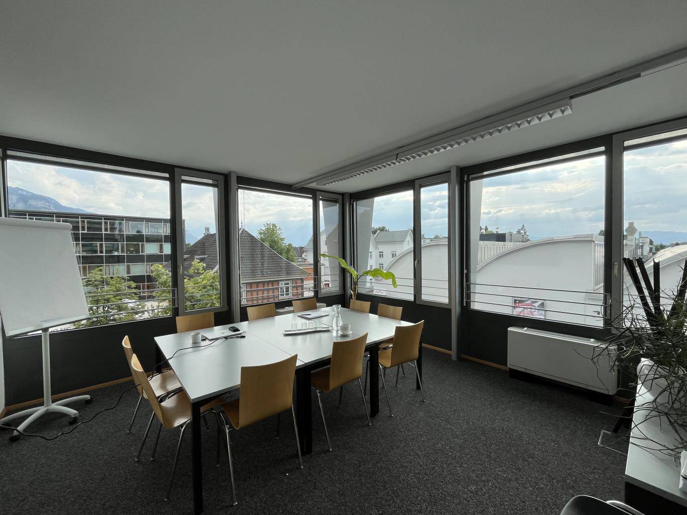 Konferenzraum mit großem Tisch, vielen Stühlen und Panoramablick auf die Stadt und Umgebung.