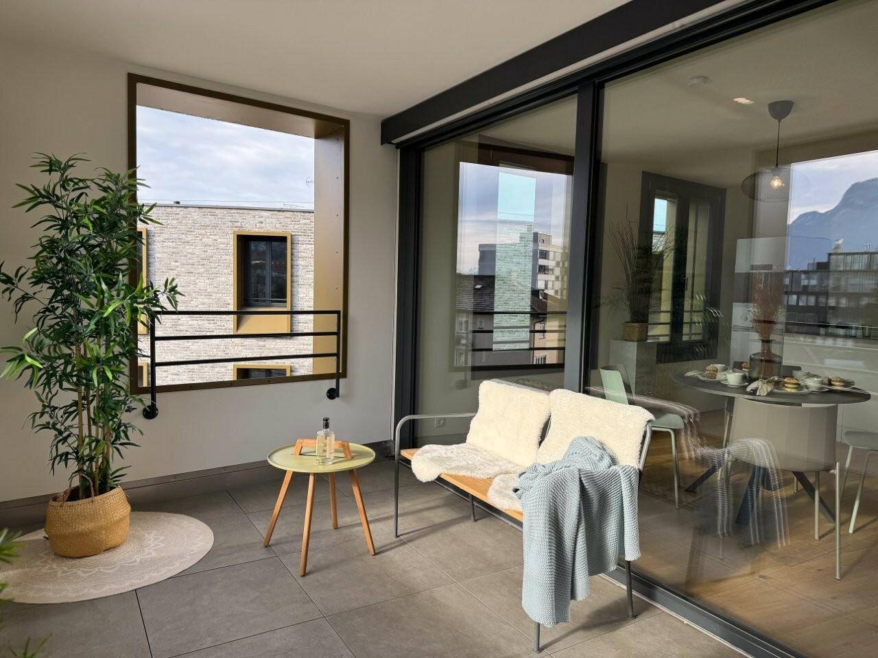 Möblierter Balkon mit Fliesenboden, Sitzgelegenheiten und Blick auf die Umgebung.