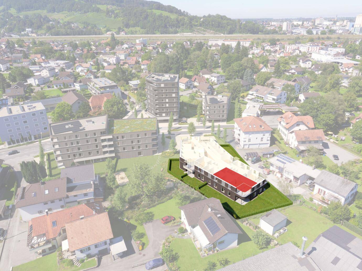Eine Luftaufnahme, die ein im Bau befindliches Gebäude mit rotem Dach und umliegende Wohngebäude zeigt (Rheindorf).