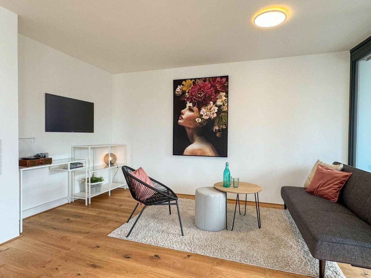 Heller Wohnbereich mit Holzboden, moderner Einrichtung und einem farbenfrohen Kunstwerk als Blickfang.