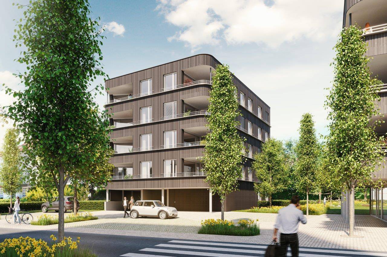 Ansicht eines modernen Mehrfamilienhauses mit dunkler Fassade, Balkonen und begrüntem Vorplatz.