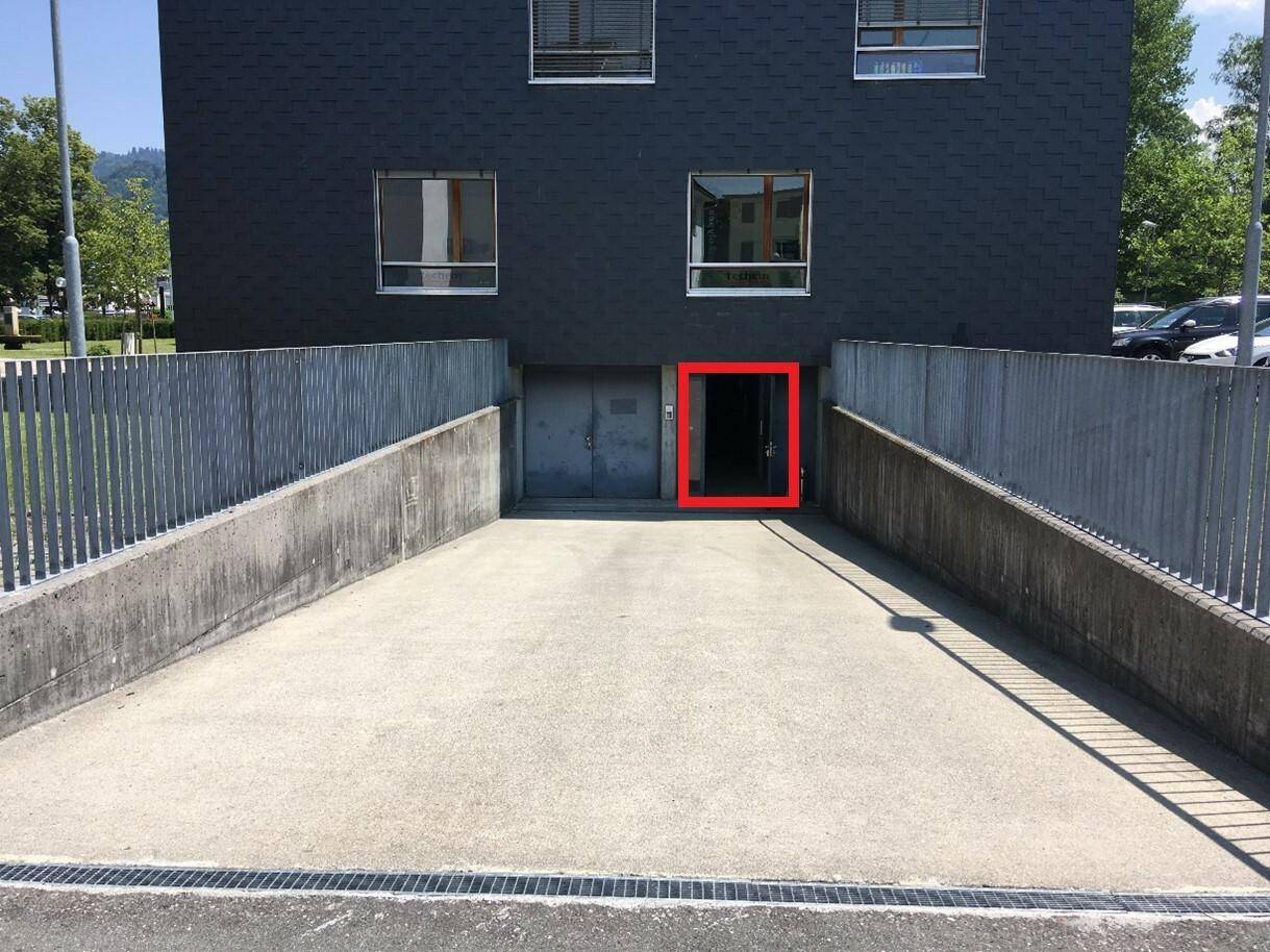 Zufahrt zu einer Tiefgarage oder einem Kellergeschoss mit Betonrampe, Metallgeländer und einem offenen Eingang.