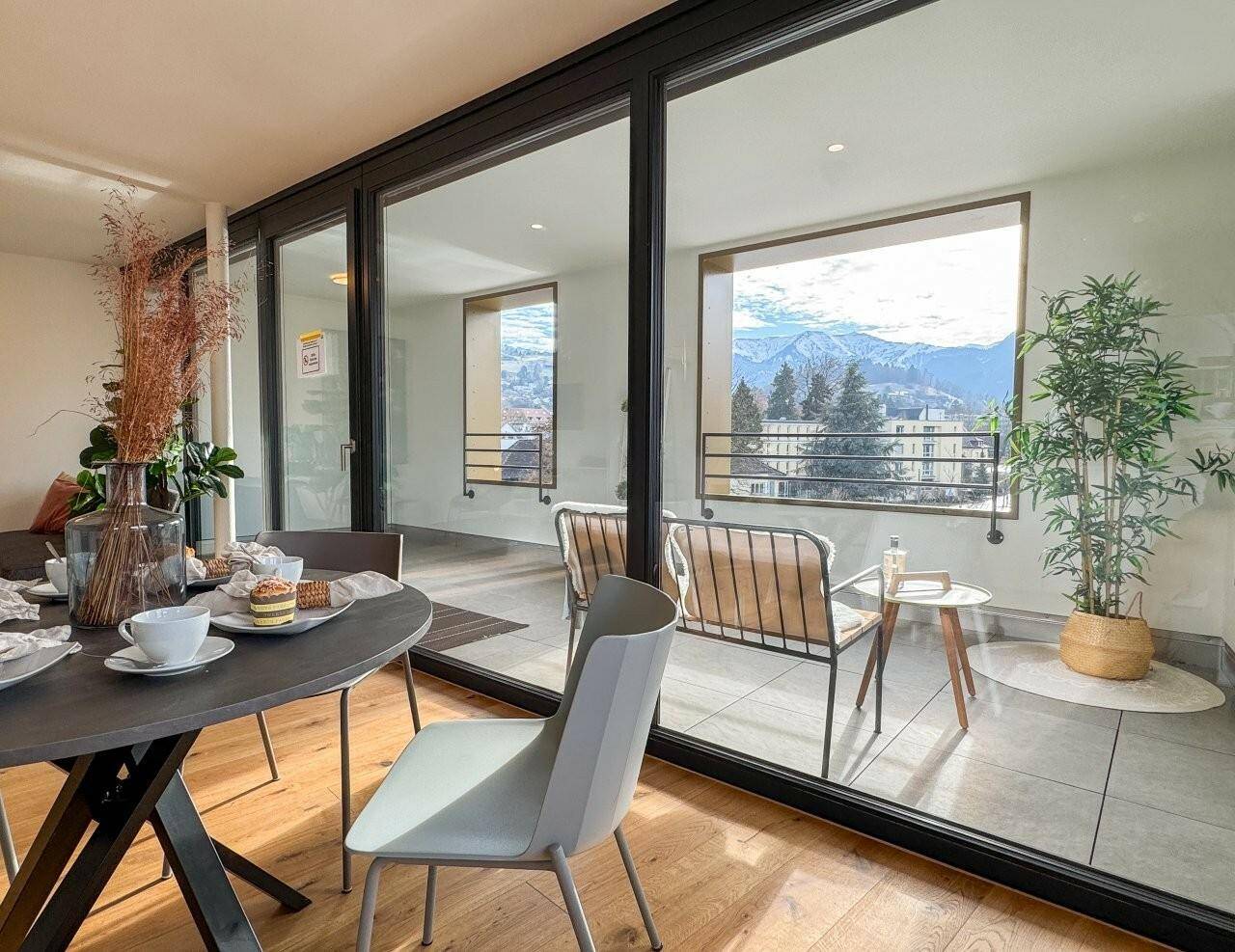 Essbereich mit Holzboden, Zugang zum Balkon und Panoramablick auf die Berge.